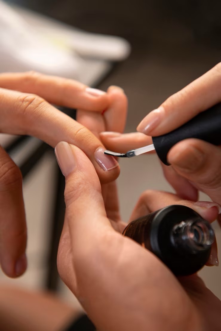 Nail technician carefully applying polish to a client's fingernail